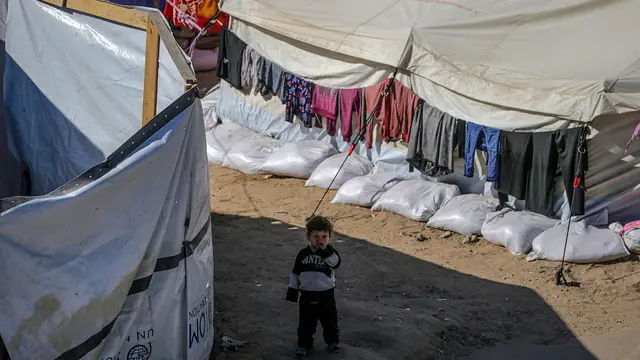 epa12075554 An internally displaced Palestinian child stands outside his family tent in Al Yarmouk stadium in central Gaza City, the Gaza Strip, 05 May 2025. According to the UN, at least 1.9 million people (or nine in ten people) across the Gaza Strip are internally displaced, including people who have been repeatedly displaced. Since October 2023, only about 11 percent of the Gaza Strip has not been placed under Israeli-issued evacuation orders, the UN aid coordination office OCHA said. EPA/MOHAMMED SABER