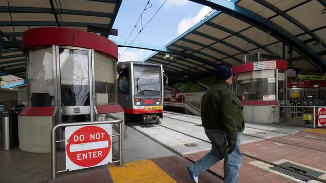 epa08327814 A pedestrian walks past a Muni light rail train at the West Portal station in San Francisco, California, USA, 27 March 2020. The San Francisco Municipal Transportation Agency (SFMTA) will temporarily discontinue using light rail Muni metro trains and subways, replacing them with buses amid the coronavirus pandemic crisis. California Governor Gavin Newsom ordered a state-wide shelter-in-place legal order directing their residents to stay at home, except for essential work, and essential needs, such as grocery shopping. EPA/JOHN G. MABANGLO