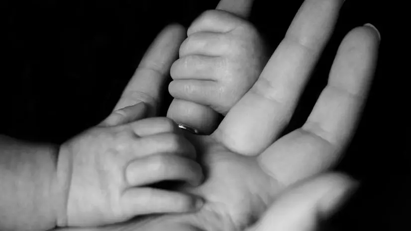 Le mani di un figlio insieme a quella di sua madre