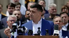 epa12112895 Presidential candidate and far-right party Alliance for the Union of Romanians (AUR) leader George Simion (C), backed by top party members and guests, speaks at a press conference with foreign media journalists held outside the Parliament Palace, during the second round of presidential elections, in Bucharest, Romania, 18 May 2025. Romanian voters are going to the polls for the runoff of the presidential election with around 18 million citizens eligible to vote, according to the Permanent Electoral Authority (AEP). EPA/ROBERT GHEMENT