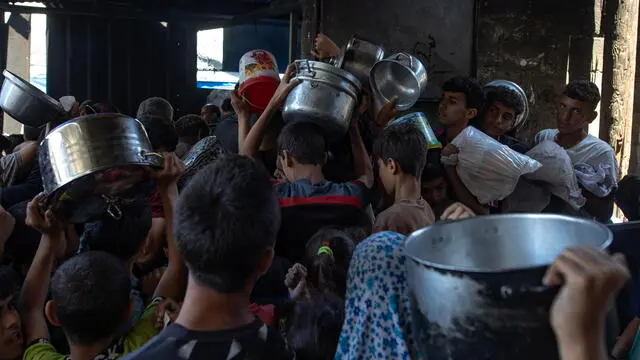 epa12122618 Hundreds of displaced Palestinians gather outside the Sokar Charity Kitchen in Gaza City to receive limited food rations,21 May, 2025. Kitchen officials say their stocks ran out today due to the suspension of humanitarian aid entering the Gaza Strip. EPA/HAITHAM IMAD