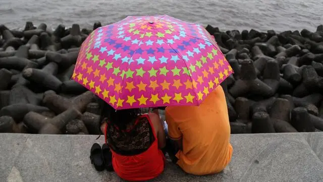 epa05433726 An Indian couple use umbrella to protect themselves during rain shower in Mumbai, India, 20 July 2016. According to reports, the India Meteorological Department (IMD) has predicted above normal forecast for this year's monsoon which runs from June to September and that accounts for about 80 per cent of India's annual rainfall. EPA/DIVYAKANT SOLANKI