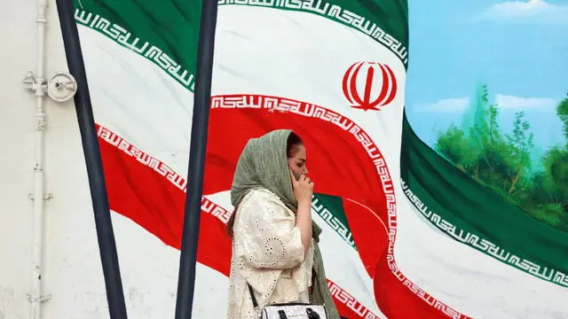 epa12121608 An Iranian woman walks past a wall painting of Iran's national flag in Tehran, Iran, 21 May 2025. Iran and US talks have paused as both sides made remarks against each other in recent days. According to the Iranian Foreign Ministry, Iranian Foreign Minister Abbas Araghchi said on 21 May 2025 that they are evaluating whether to participate in the next round of negotiations. He added that Iran has already responded to unreasonable demands and that such remarks do not help the talks. Our position is clear: uranium enrichment will continue, whether or not there is an agreement. EPA/ABEDIN TAHERKENAREH