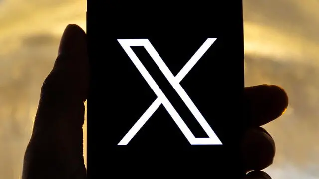 epa10772439 An illustration pictures shows a user holding a mobile phone displaying the 'X' logo, in Los Angeles, California, USA, 27 July 2023. Twitter announced on 23 July that it will rebrand to X. EPA/ETIENNE LAURENT