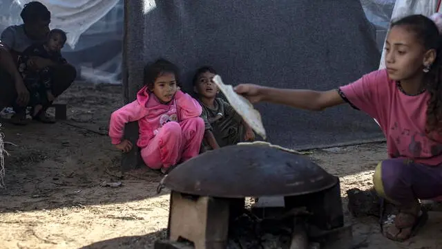 epa10976545 Palestinians wait as bread is being prepared after a rainy night inside a tent complex at a camp provided by the United Nations Development Program (UNDP) for displaced Palestinians who lost their homes in Israeli strikes, in Khan Yunis, 15 November 2023. More than 11,000 Palestinians and at least 1,400 Israelis have been killed, according to the Israel Defense Forces (IDF) and the Palestinian health authority, since Hamas militants launched an attack against Israel from the Gaza Strip on 07 October, and the Israeli operations in Gaza and the West Bank which followed it. EPA/HAITHAM IMAD