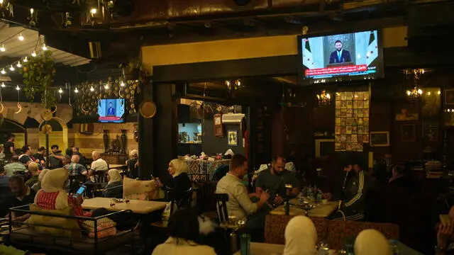 epa12100750 Syrians watch a speech by Syrian President Ahmad al-Sharaa, after Trump's decision to lift sanctions on Syria, at Al-Rawda Cafe in central Damascus, Syria, 14 May 2025. EPA/AHMAD FALLAHA