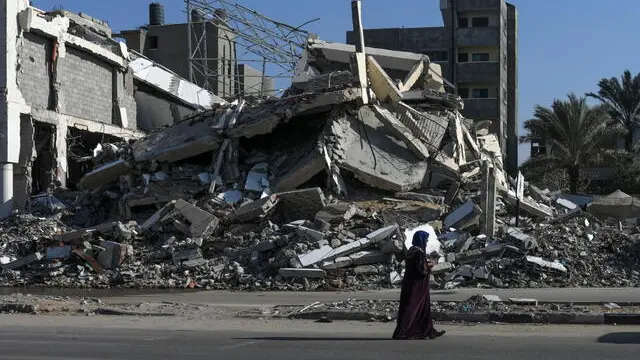 epa11733420 A woman walks past destroyed houses in the Al Bureij refugee camp, central Gaza Strip, 21 November 2024. More than 44,000 Palestinians, including over 13,000 children, have been killed according to the Palestinian Ministry of Health and over 1,400 Israelis have been killed according to the Israel Defense Forces (IDF), since Hamas militants launched an attack against Israel from the Gaza Strip on 07 October 2023, and the Israeli operations in Gaza and the West Bank which followed it. EPA/MOHAMMED SABER