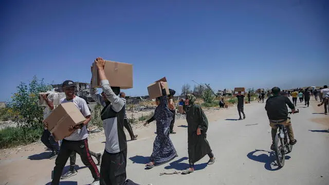 epa12143218 Palestinians carry aid supplies received from the US-backed Gaza Humanitarian Foundation through an area known as the Netzarim Corridor, central Gaza Strip, 29 May 2025. According to the UN half a million people, or one in five people in the Strip are facing starvation while the entire population of the Gaza Strip continues to face a critical risk of famine following 19 months of conflict, mass displacement and severe restrictions on humanitarian aid. EPA/HAITHAM IMAD