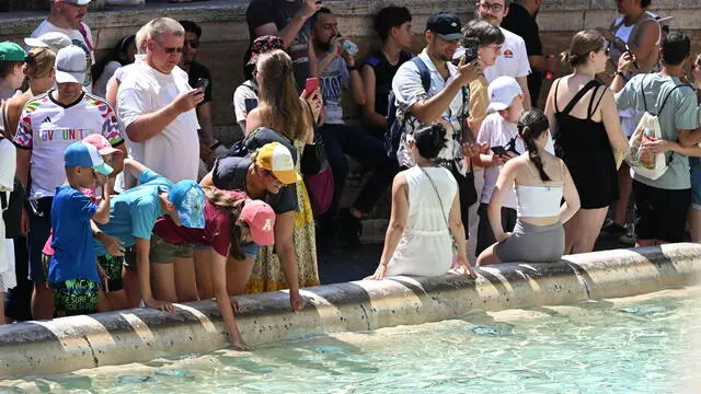 Turisti nella morsa del caldo a Fontana di Trevi. Roma, 13 agosto 2024. ANSA/CLAUDIO PERI