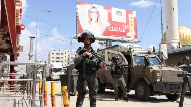 epa10543931 Israeli border police stand guard during protests by Palestinians and Israeli settlers in Huwara, near the West Bank city of Nablus, 26 March 2023. A Palestinian house was set on fire near Ramallah following a shooting incident in which, according to the IDF, two soldiers were shot at and wounded in the town of Huwara on the night of 25 March. EPA/ALAA BADARNEH