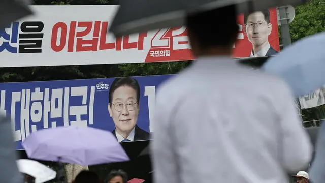 epa12150143 Pedestrians walk past banners depicting presidential candidates Kim Moon-soo (R) of the People Power Party and Lee Jae-myung (C) of the Democratic Party along a street in Seoul, South Korea, 02 June 2025. South Korea will hold its presidential election on 03 June 2025. EPA/ANDRES MARTINEZ CASARES