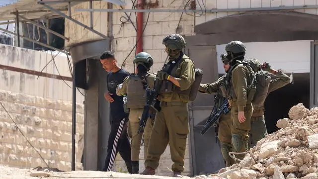 epa12143242 Israeli soldiers detain a Palestinian man as he makes his way home during an Israeli military operation in the Tulkarem refugee camp, near the West Bank city of Tulkarem, 29 May 2025. According to the Palestinian news agency Wafa, Israeli forces continued their operation in the city of Tulkarem and its refugee camp demolishing dozens of residential buildings. EPA/ALAA BADARNEH