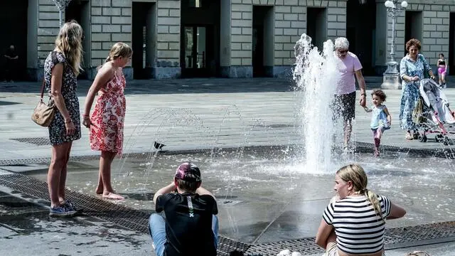 Le persone cercano refrigerio all'ombra o in una fontana dalle alte temperature mperature per il caldo estivo. Torino 11 luglio 2024 ANSA/TINO ROMANO