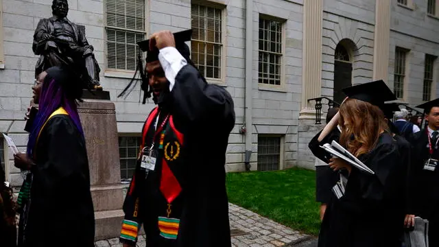 epa12143251 Graduates tip their caps as they walk past the statue of John Harvard in preparation for the 374th Commencement ceremonies at Harvard University in Cambridge, Massachusetts, USA, 29 May 2025. EPA/CJ GUNTHER