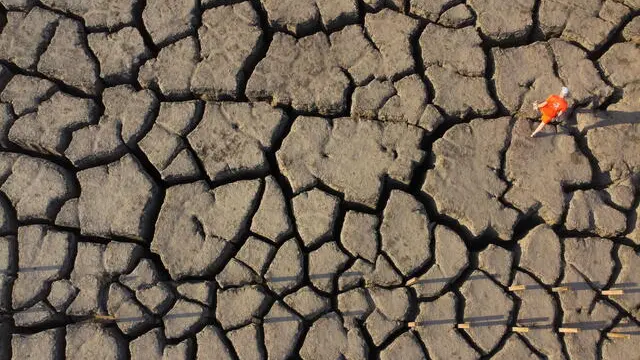 epa11282593 A picture taken with a drone shows a person walking on a dry cliff in an abandoned quarry near Timna Park outside the city of Eilat, Israel, 16 April 2024. After the closure of the Timna copper mine in the 1980s, one of the quarries was flooded with groundwater, creating a huge lake. EPA/ABIR SULTAN