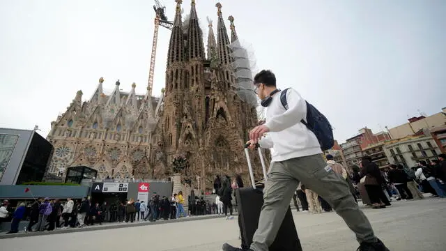 epa11927731 A tourist walks in front of the 'Sagrada Familia' cathedral in Barcelona, Spain, 27 February 2025. Catalonia will double the tourist tax following an agreement reached by the regional government and the Comuns (Commons) party. A part of the income will be allocated to the housing crisis. EPA/Alejandro Garcia