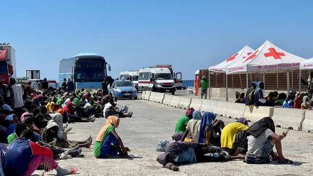 Dall'hotspot all'area di presidio dei vigili del fuoco, 400 forse 500 metri di strada - in contrada Imbriacola a Lampedusa - ricolmi di coperte termiche, scarpe, bottigliette d'acqua vuote, indumenti e tovaglie, dove aleggia un odore nauseabondo. E' un "mare umano" - scortato dai volontari della Croce Rossa - quello che anche stamattina è stato spostato perché è proprio dall'area dei vigili del fuoco che i migranti vengono caricati sugli autobus per raggiungere il porto dove verranno imbarcati su navi militari e traghetti di linea, 14 settembre 2023. ANSA/ELIO DESIDERIO