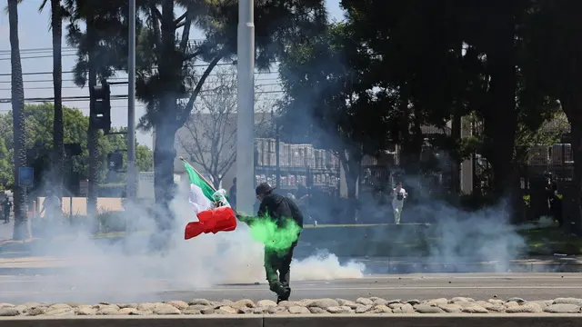 epa12163148 A protester holds a Mexican flag during a clash with federal agents near a Home Depot after a raid was conducted by Immigration and Customs Enforcement (ICE) in Paramount, California, USA, 07 June 2025. This comes the day after federal immigration authorities arrested more than 40 people across Los Angeles, as protesters gathered outside a federal detention center. EPA/ALLISON DINNER
