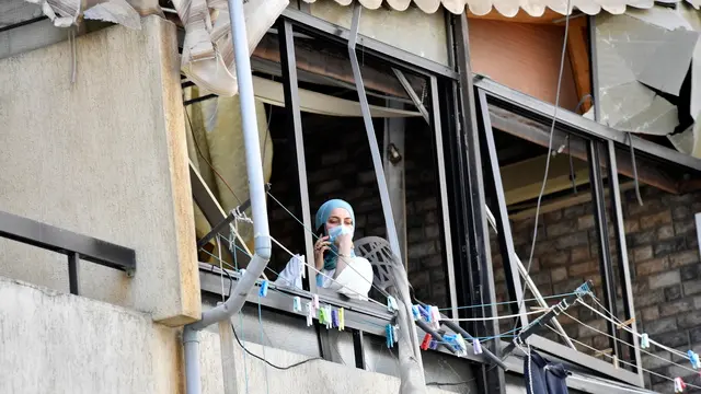 epa12159588 A woman looks out a window near a damaged building following an Israeli airstrike in the Dahieh district in southern Beirut, Lebanon, 06 June 2025. The Israel army stated the renewed strikes in the southern suburb of Beirut were carried out against alleged Hezbollah drone facilities established in civilian neighborhoods. EPA/STRINGER