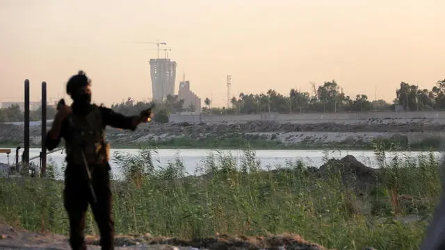 epa09250223 A member of Iraqi special forces stands guard with the heavily fortified Green Zone, which houses the Iraqi government offices and the US embassy and other international diplomatic missions, in the background, in central Baghdad, Iraq, 05 June 2021. EPA/AHMED JALIL