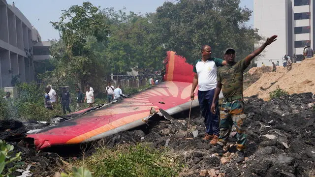epa12171228 People stand near debris at the site of a plane crash near Sardar Vallabhbhai Patel International Airport in Ahmedabad, Gujarat, western India, 12 June 2025. Air India flight AI171, bound for London carrying 242 passengers and crew members on board a Boeing 787-8 aircraft, crashed minutes after take-off in the Meghaninagar area of Ahmedabad. EPA/SIDDHARAJ SOLANKI
