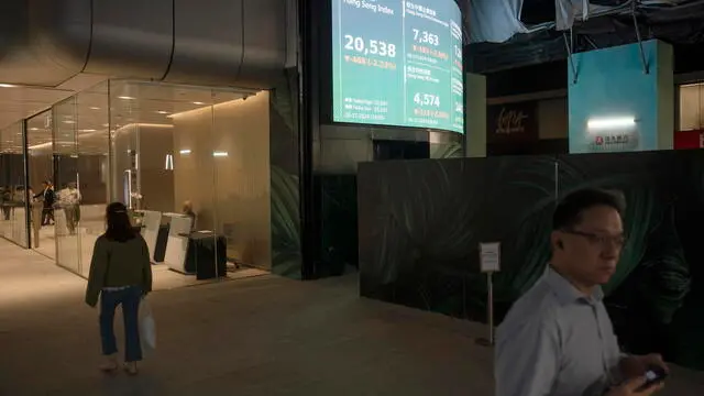 epa11705283 Pedestrians walk past a screen showing the Hang Seng index in Hong Kong, China, 06 November 2024. A few hours after the preliminary US presidential results were announced, Hong Kong's stock market, the Hang Seng Index, fell 2.23 percent. EPA/LEUNG MAN HEI