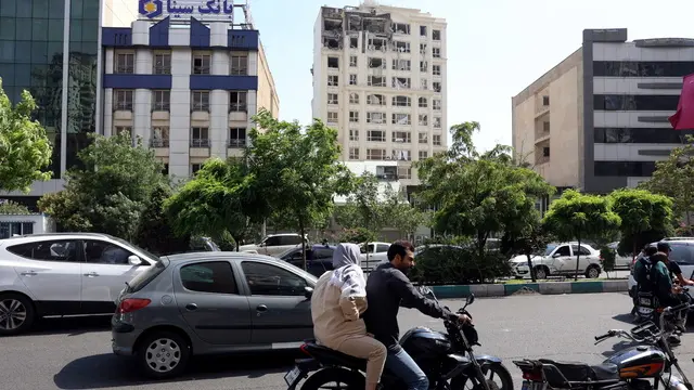 epa12173191 People commute past a damaged building that was hit by Israeli air strikes, north of Tehran, Iran, 13 June 2025. Israel launched strikes on Iran and its capital Tehran early 13 June, killing top military figures, including Armed Forces Chiefs of Staff Mohammad Bagheri and Chief Commander of the Islamic Revolutionary Guard Corps (IRGC) Hossein Salami, both countries confirmed. The strikes were part of Operation Rising Lion, Israel's Prime Minister Netanyahu said, adding that Iran's nuclear programme poses a threat to 'Israel's very survival.' EPA/ABEDIN TAHERKENAREH