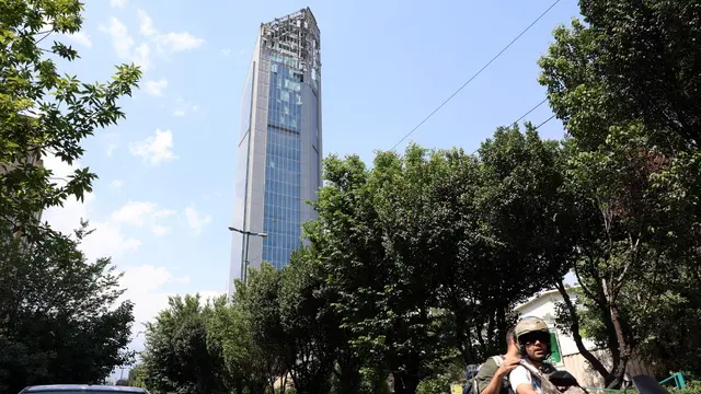 epa12173185 People pass by a damaged high-rise building that was hit by Israeli air strikes, north of Tehran, Iran, 13 June 2025. Israel launched strikes on Iran and its capital Tehran early 13 June, killing top military figures, including Armed Forces Chiefs of Staff Mohammad Bagheri and Chief Commander of the Islamic Revolutionary Guard Corps (IRGC) Hossein Salami, both countries confirmed. The strikes were part of Operation Rising Lion, Israel's Prime Minister Netanyahu said, adding that Iran's nuclear programme poses a threat to 'Israel's very survival.' EPA/ABEDIN TAHERKENAREH