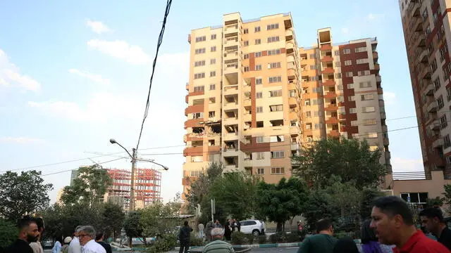 epa12172704 People gather outside a building that was hit by Israeli air stikes north of Tehran, Iran, 13 June 2025. Israel confirms it has launched strikes on Iran's 'nuclear program' as blasts are heard across the country. The strikes are part of Operation Rising Lion, Israel's Prime Minister Benjamin Netanyahu said, adding Iran was a threat to "Israel's very survival". EPA/ABEDIN TAHERKENAREH