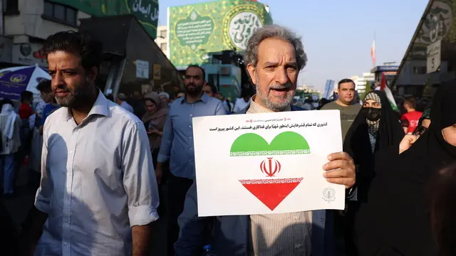 epa12175423 A man holds a placard reading in Persian 'a country whose entire population is ready to sacrifice is a victorious country' during an anti-Israel rally in Tehran, Iran, 14 June 2025. Israel launched strikes on Iran's nuclear and military facilities on 13 June, targeting top generals and scientists. In retaliation, Iran launched waves of missiles and drones toward Israel. EPA/ABEDIN TAHERKENAREH
