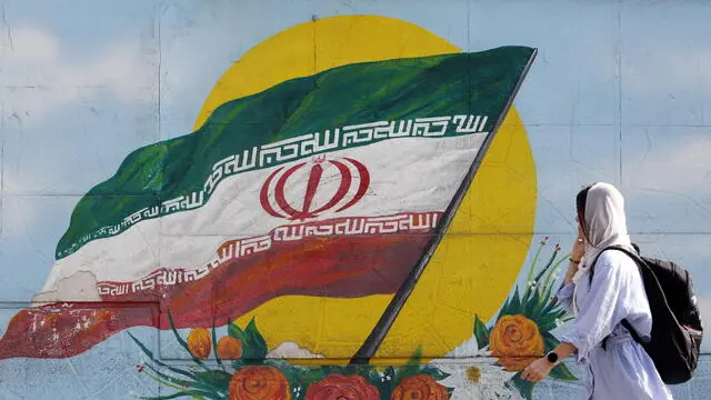 epa10295546 A woman walks past a graffiti showing the Iranian national flag in Tehran, Iran, 09 November 2022. Iran has been rocked by anti-government protests, with supporters worldwide, following the death in September 2022 of Masha Amini, a 22-year-old girl who died while in police custody after being detained for breaking Iran's strict dress code for women. Iranian leaders condemned the protests and accused the United States and Israel of planning the uprising. EPA/ABEDIN TAHERKENAREH