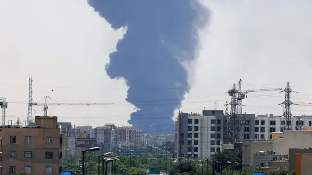 epa12176951 Smoke from an oil refinery rises over residential buildings in southern Tehran, Iran, 15 June 2025. Israel continued to target sites related to Iran's nuclear program and energy facilities, after launching strikes across Iran since 13 June. In retaliation, Iran launched waves of missiles and drones toward Israel. EPA/ABEDIN TAHERKENAREH