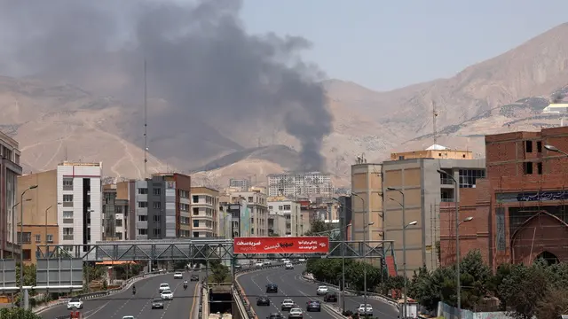epa12178551 Cars drive along a motorway as smoke rises in the background from an oil refinery, northwest of Tehran, Iran, 16 June 2025. Israel and Iran have been exchanging fire since Israel launched strikes across Iran on 13 June 2025 as part of Operation 'Rising Lion.' EPA/ABEDIN TAHERKENAREH