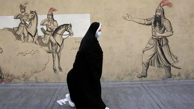 epa10234551 A veiled Iranian woman walkS past a wall painting in a street in Tehran, Iran, 10 October 2022. Iran has been facing worldwide anti-government protests following the death of Masha Amini, a 22 year old girl, who was detained on 13 September by the police unit responsible for enforcing Iran's strict dress code for women. Amini was declared dead on 16 September, after she spent 3 days in a coma. Iranian leaders condemned the protests as 'riots' and accused US and Israel for planning the protests inside the country. EPA/ABEDIN TAHERKENAREH