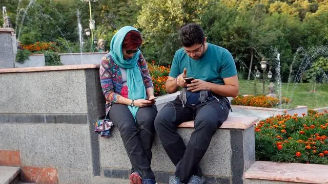 epa05477279 A young Iranian couple play 'Pokemon Go' on their smartphones at the Mellat Park, northern Tehran, Iran, 12 August 2016. Media reported that Iranian officials have banned the popular mobile device game 'Pokemon Go' for security reasons. The security agencies and the Department of Internet crime were unanimously in their conclusion that 'Pokemon Go' is a dangerous game and must therefore be prohibited. Social networks such as Facebook and Twitter are also banned in Iran and people need to use VPN and Proxy to connect them. EPA/ABEDIN.TAHERKENAREH