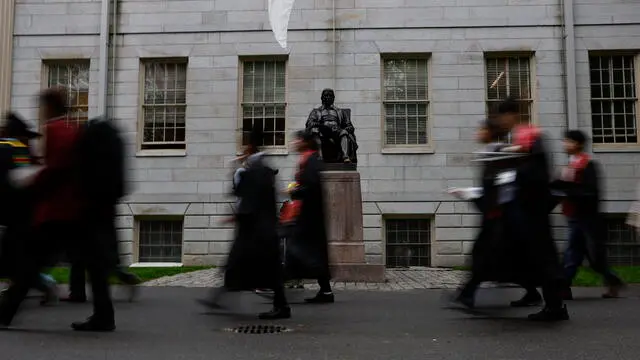 epa12143257 Graduates walk past the statue of Joh Harvard in preparation for the 374th Commencement ceremonies at Harvard University in Cambridge, Massachusetts, USA, 29 May 2025. EPA/CJ GUNTHER