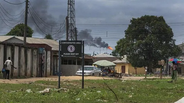 epa05203260 A general view of the Ogale community with a sign warning of contaminated land and an oil flare in the distance in the oil rich Niger Delta, Nigeria, 09 March 2016. Oil company Shell is being sued in London for the second time in five years over spills in the Niger Delta. The Ogale community of around 40,000 people in Rivers State in the Niger Delta are predominantly farmers or fishermen and are some of the claimants wanting Shell to clean up their land. Their case is being handled by law firm Leigh Day. Spills since 1989 have meant they don't have clean drinking water, farmland or rivers according to their claim. A November 2015 report by Amnesty International indicates four spill sites Shell said it planned cleaning up are still contaminated. EPA/TIFE OWOLABI