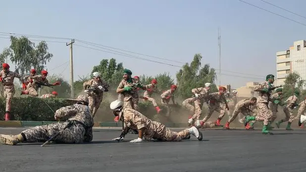 epa07039277 Iranian soldiers jump over a hedge at a street as they run for cover during a terror attack that occurred during a military parade in the city of Ahvaz, southwest Iran, 22 September 2018. According to media reports, gunmen have opened fire during an Iranian military parade in the south-western city of Ahvaz, killing at least 25 people, including civilians, and injuring dozens. EPA/MORTEZA JABERIAN