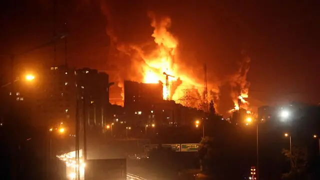 epa12176394 People drive as fire and smoke rise from Tehranâ€™s oil warehouse in Tehran, Iran, 15 June 2024. Israel continues strikes on Iranâ€™s nuclear program and energy facilities. EPA/ABEDIN TAHERKENAREH