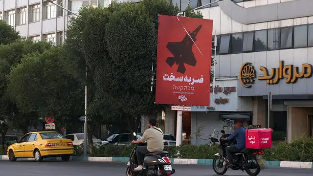 epa12192843 Iranians on motorbikes pass a billboard reading 'Harsh Response', in Tehran, Iran, 23 June 2025. The US forces struck three of Iran's key nuclear sites: Natanz, Isfahan and Fordo, US President Trump announced on 21 June. Israel and Iran have been exchanging fire since Israel launched strikes across Iran on 13 June 2025 as part of Operation 'Rising Lion.' EPA/ABEDIN TAHERKENAREH
