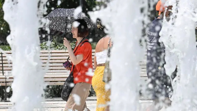 Una turista cammina proteggendosi dal sole con un ombrello in Piazza Castello, Milano, 13 giugno 2025. ANSA/DANIEL DAL ZENNARO