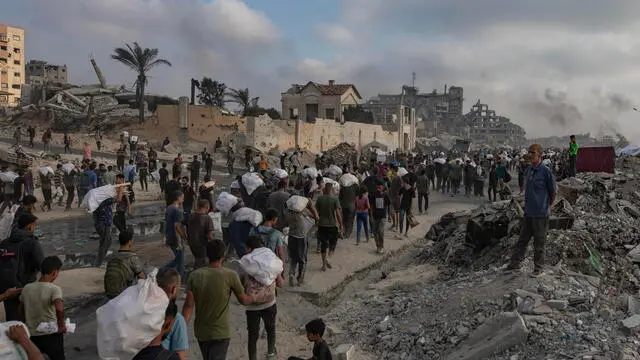 epa12191493 Displaced Palestinians carry relief packages along Rashid Street, west of Jabalia, 22 June 2025, after humanitarian aid trucks entered the northern Gaza Strip through the Israeli-controlled Zikim crossing, northwest of Gaza City. More than 55,700 Palestinians have been killed in the Gaza Strip, according to the Palestinian Ministry of Health, since Israel launched a military campaign in the strip in response to a cross-border attack led by the Palestinian militant group Hamas on 07 October 2023. EPA/HAITHAM IMAD