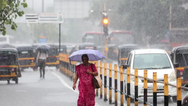 epa12179164 An Indian woman uses an umbrella to cover herself during heavy rain in Mumbai, India, 16 June 2025. The India Meteorological Department (IMD) issued an orange alert on 16 June for heavy to very heavy rainfall in Mumbai and adjacent districts. EPA/DIVYAKANT SOLANKI