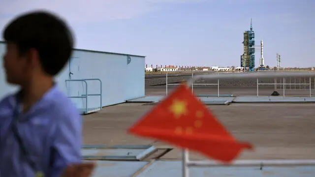 epa12050824 A boy holds a Chinese flag in front of the Long March 2F rocket carrying the Shenzhou-20 space mission before its launch at the Jiuquan Satellite Launch Center, near Jiuquan, China, 24 April 2025. EPA/ANDRES MARTINEZ CASARES