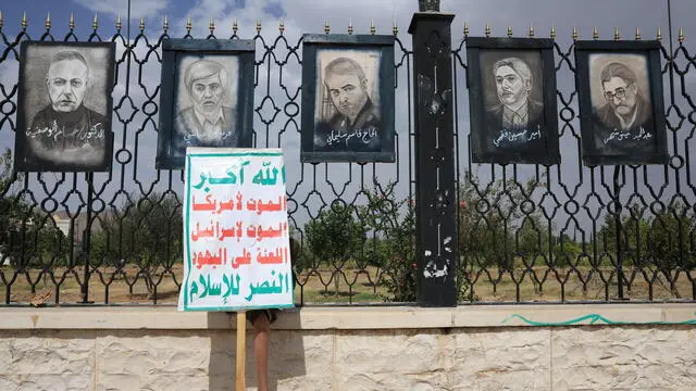 epa12201962 A Houthi supporter takes shelter from the sun with an anti-US and Israel placard beneath paintings depicting portraits of Iranian generals and nuclear scientists who were killed in Israeli airstrikes, in Sana'a, Yemen, 27 June 2025. A US-mediated ceasefire between Iran and Israel started on 24 June, ending a conflict that began on 13 June after Israel conducted a campaign across Iran targeting nuclear, military, and energy facilities, prompting Iran to launch retaliatory waves of missiles and drones toward Israel. EPA/YAHYA ARHAB