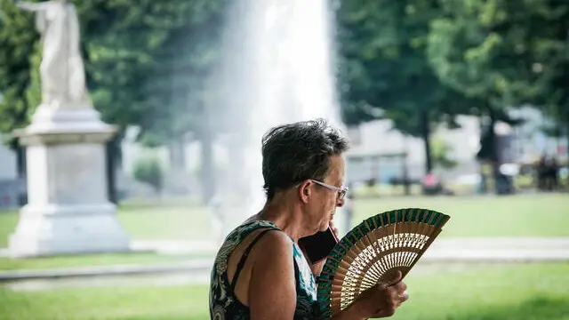 Una donna con il ventaglio per difendersi dal caldo afoso estivo. Torino 13 giugno 2025 ANSA/TINO ROMANO