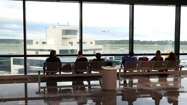 Alcuni passeggeri osservano un aereo che decolla dal terminal dell'aeroporto di Malpensa che nel pomeriggio a causa della forte pioggia si è allagato in diversi punti, 15 maggio 2015. ANSA / MATTEO BAZZI