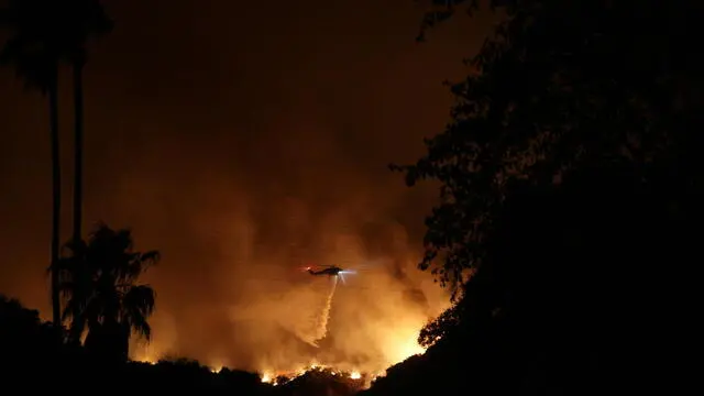 epa11817871 A helicopter does a night water drop over the Palisades wildfire in the Mandeville Canyon area of Los Angeles, California, USA, 10 January 2025. Multiple wildfires continue to burn across thousands of acres in Southern California, destroying thousands of homes and forcing people to evacuate areas throughout the Los Angeles area. According to the California Governor’s office, more than 7,500 firefighting and emergency personnel are involved in response efforts. EPA/ALLISON DINNER