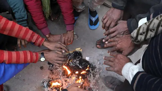 epa11053030 Indian people warm themselves near a fire during a cold winter morning in New Delhi, India, 02 January 2024. Winter takes a heavy toll each year around northern India, as poverty forces many homeless people to live outdoors. Temperatures in the northern Indian regions continue to decrease. EPA/RAJAT GUPTA