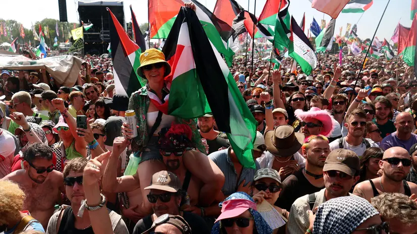 epa12203228 Kneecap fans carry Palestinian flags as they watch Kneecap perform at the West Holts stage during day four of the Glastonbury Festival at Worthy Farm near Pilton, Somerset, Britain, 28 June 2025. The Glastonbury Festival of Contemporary Performing Arts 2025 runs from 25 to 29 June 2025. EPA/ANDY RAIN